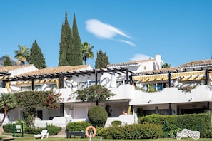 Un hotel con paredes exteriores blancas, tejas de barro cocido y una zona de estar cubierta al aire libre.