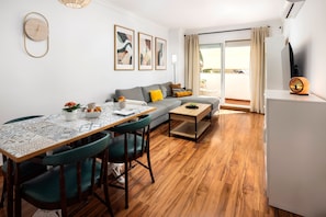 Una sala moderna con una mesa de comedor, sillas, un sofá y un televisor.