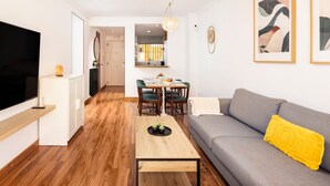 A modern living room with a grey sofa, a wooden coffee table, and a dining area with a table and chairs. - AS EXT BMD Jardines Torrequebrada II 2F (Benalmádena)