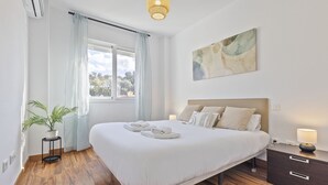 A bedroom with a large bed, bedside tables, a potted plant, and a window with curtains. - AS EXT BMD Jardines Torrequebrada II 2F (Benalmádena)