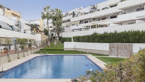 A residential area with a swimming pool, white buildings, and a palm tree. - AS EXT BMD Jardines Torrequebrada II 2F (Benalmádena)