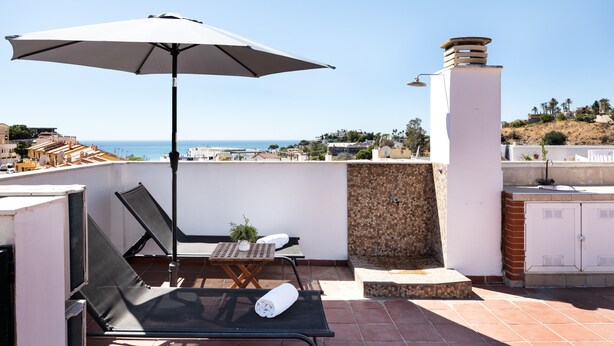 A rooftop terrace with a table, chairs, an umbrella, and a view of the sea. - AS EXT BMD Jardines Torrequebrada II 2F (Benalmádena)