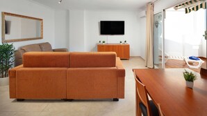 Una sala de estar moderna con un sofá, un televisor, un mueble de madera y un comedor.