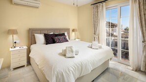 A hotel room with a large bed, two bedside tables, a window with curtains, and a view of buildings. - AS EXT Mijas Puebla Aida 12L (Mijas)