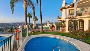 A pool area with two pools, palm trees, and a building with balconies. - AS EXT Mijas Puebla Aida 12L (Mijas)