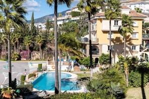 A residential area with a swimming pool surrounded by palm trees and a multi-story building with balconies. - AS EXT Mijas Puebla Aida 12L (Mijas)