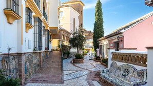 A narrow alleyway with tiled flooring, a mosaic bench, and traditional buildings with balconies. - AS EXT Mijas Puebla Aida 12L (Mijas)