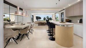 A modern kitchen with a central island, bar stools, and a view of the outdoors. - AS EXT CBP Granados 1201 (Mijas)