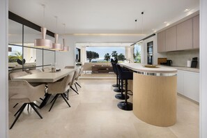 Una cocina moderna con una isla central, taburetes de bar y vistas al exterior.