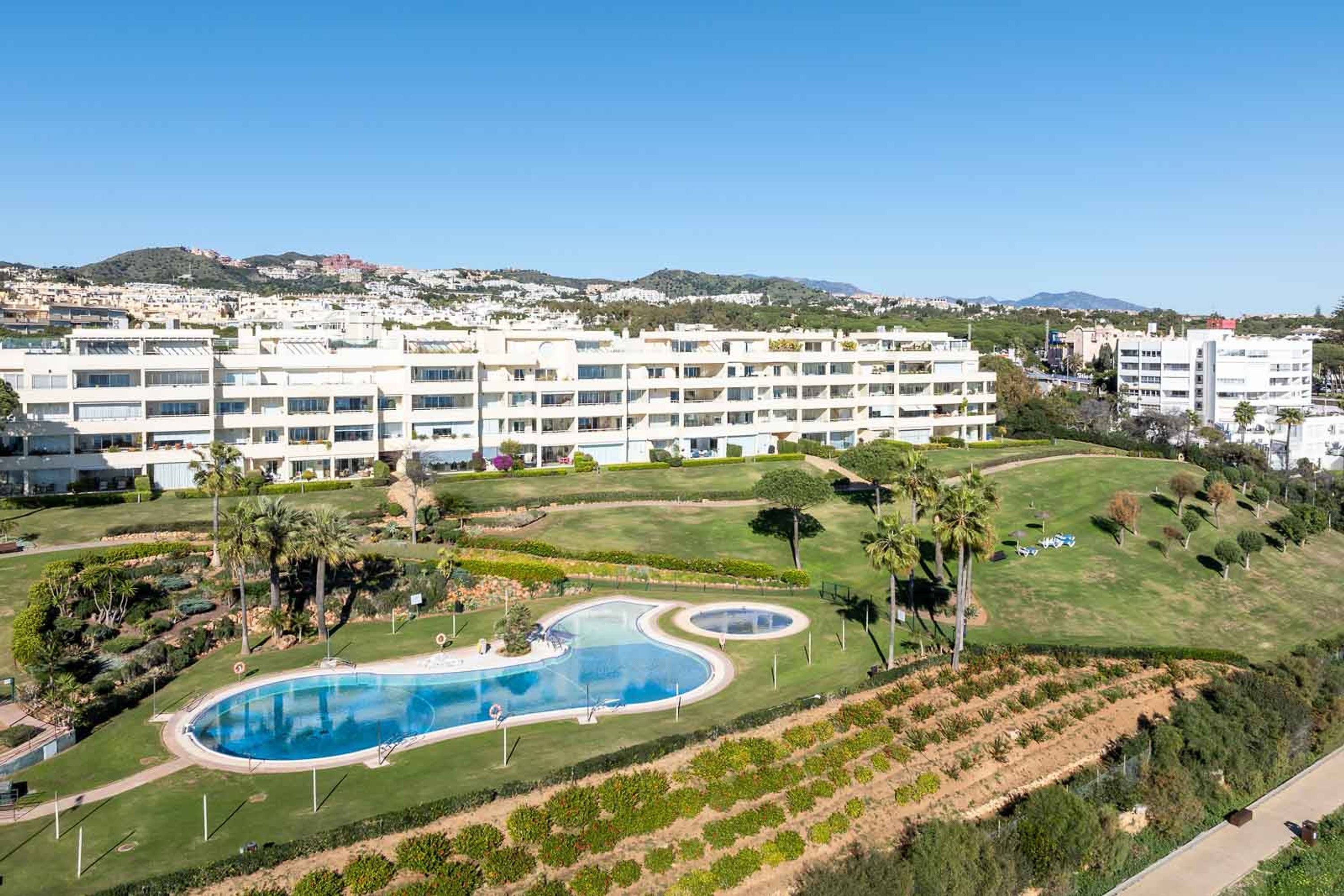 A hotel with multiple floors, a swimming pool, and landscaped gardens.