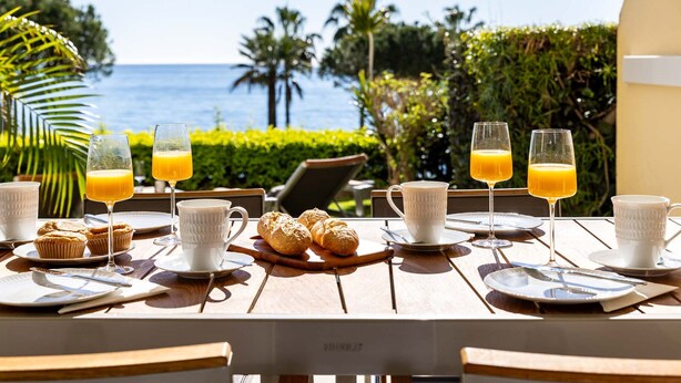 A breakfast table set with croissants, orange juice, and coffee cups, overlooking a scenic ocean view. - AS EXT CBP Granados 1201 (Mijas)