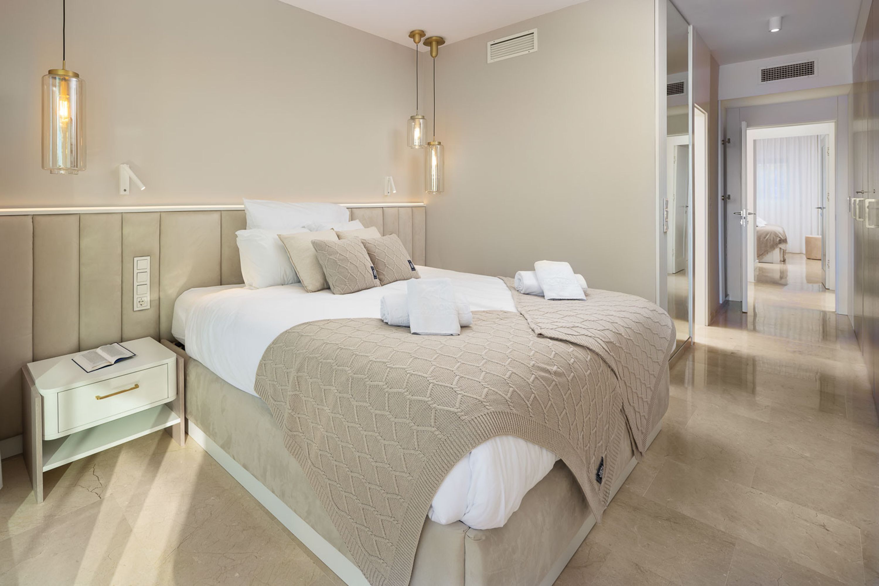 Un dormitorio moderno con una cama grande, mesitas de noche y un vestidor.