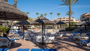A resort pool area with sun loungers, thatched umbrellas, and palm trees. - AS MDM 3 in Mijas Costa (Mijas)