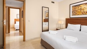 A hotel room with a large bed, a bedside table with a lamp, a mirror, and a door leading to another room. - AS MD 5D3 in Mijas Costa (Mijas)