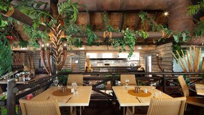 A restaurant with high ceilings, hanging plants, wicker furniture, and a brick wall. - AS MD 5D3 in Mijas Costa (Mijas)
