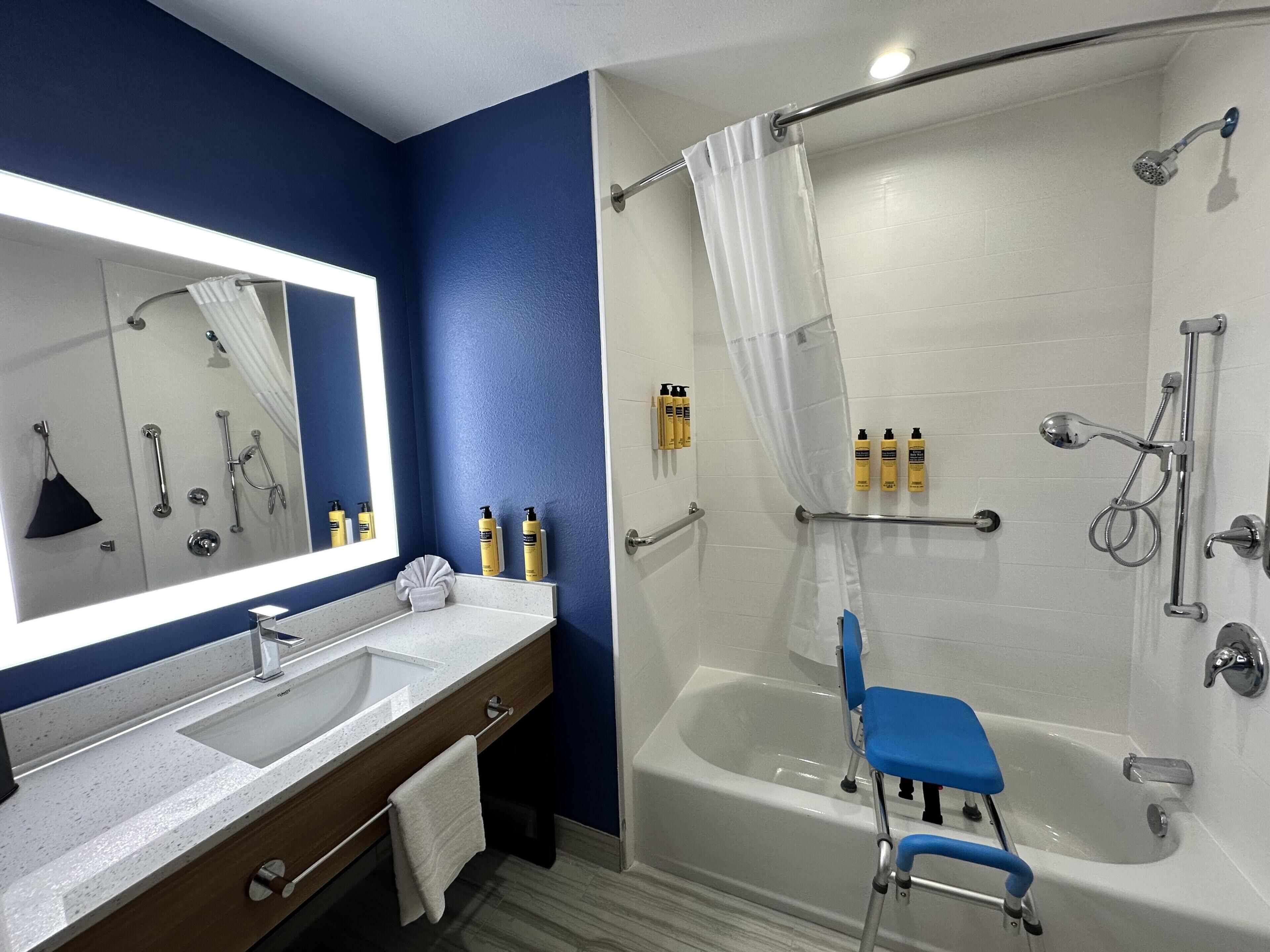 Un baño con bañera, ducha, tocador con espejo y artículos de aseo.