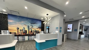 Un área de recepción con un mural de la ciudad, un mostrador de recepción y una lámpara moderna.