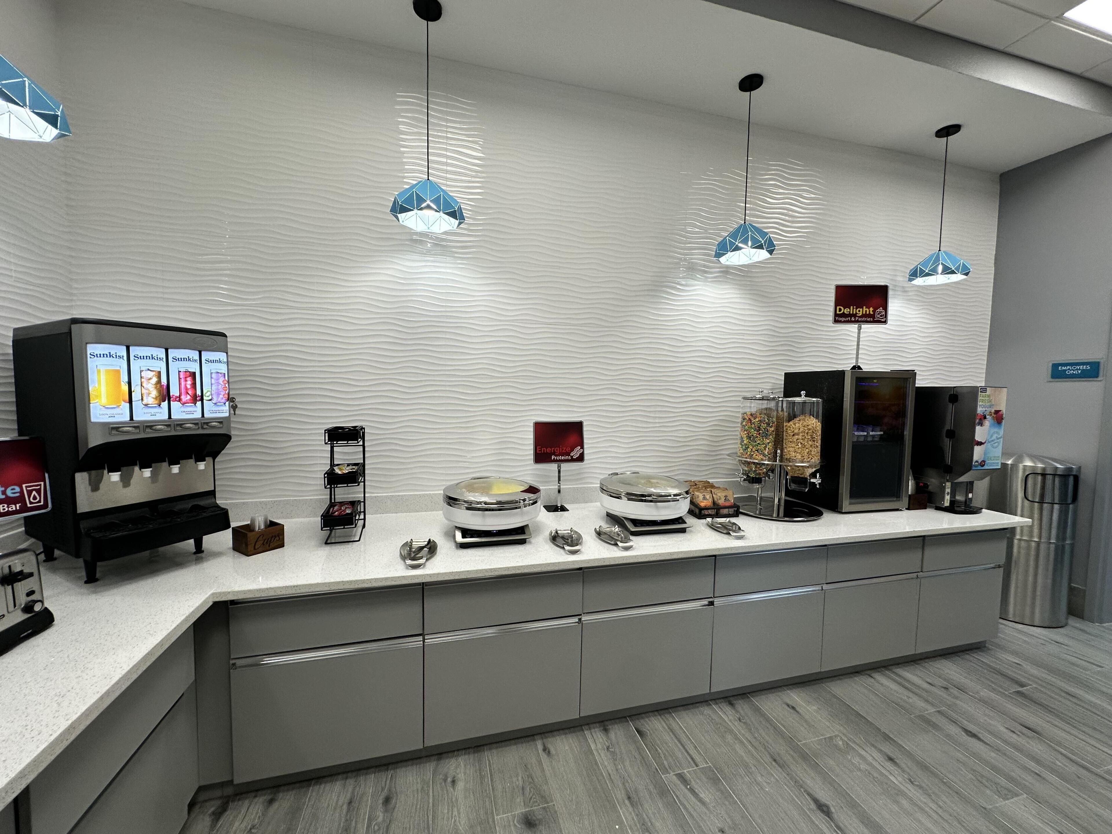 Um balcão de café da manhã moderno com dispensador de bebidas, uma balança e um espaço com iogurtes.