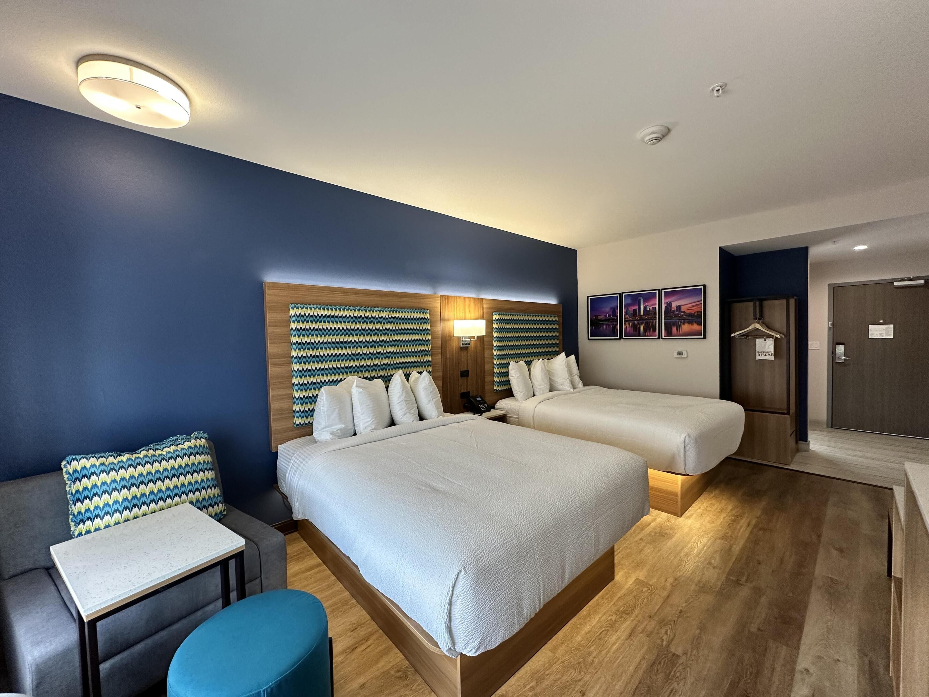 Habitación de hotel con dos camas, una mesita, un sofá y un armario.