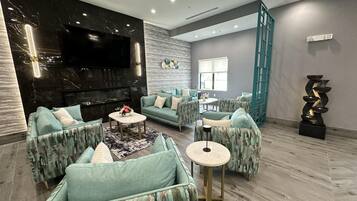 A modern living room with a flat-screen TV, patterned sofas, a coffee table, and a decorative water feature.