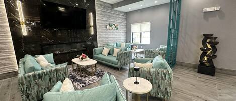 A modern living room with a flat-screen TV, patterned sofas, a coffee table, and a decorative water feature.