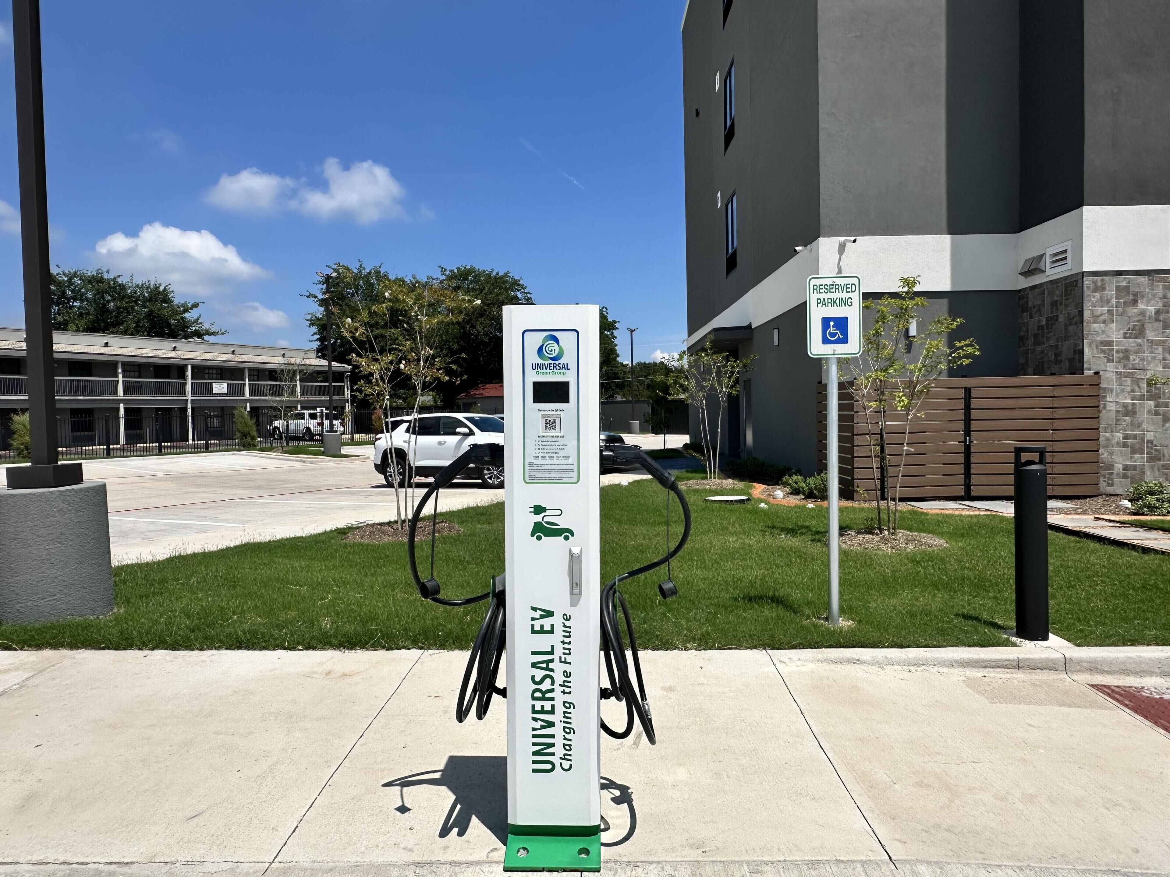 An electric vehicle charging station labeled 'Universal EV' with a sign indicating reserved parking for disabled individuals.