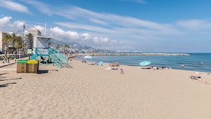 A beach with a lifeguard tower, umbrellas, and people sunbathing. - AS EXT Fgrl PYR 1004 (Fuengirola)