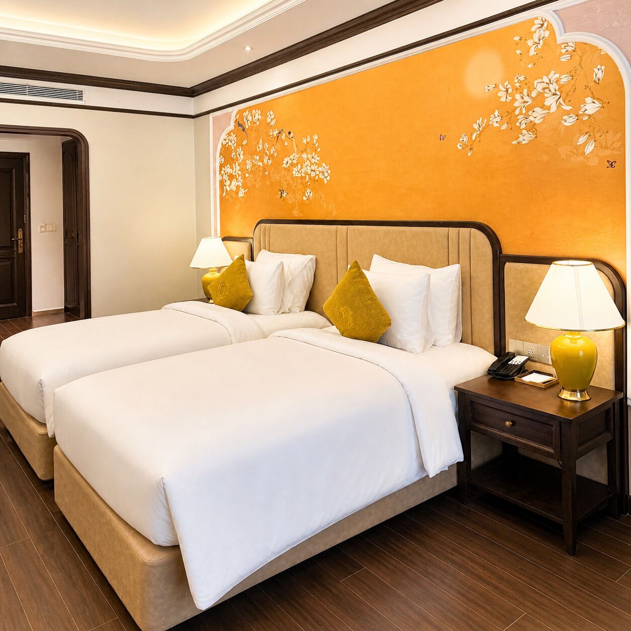 Una cama doble con ropa de cama blanca, dos mesitas de noche con lámparas y una pared con un mural floral.