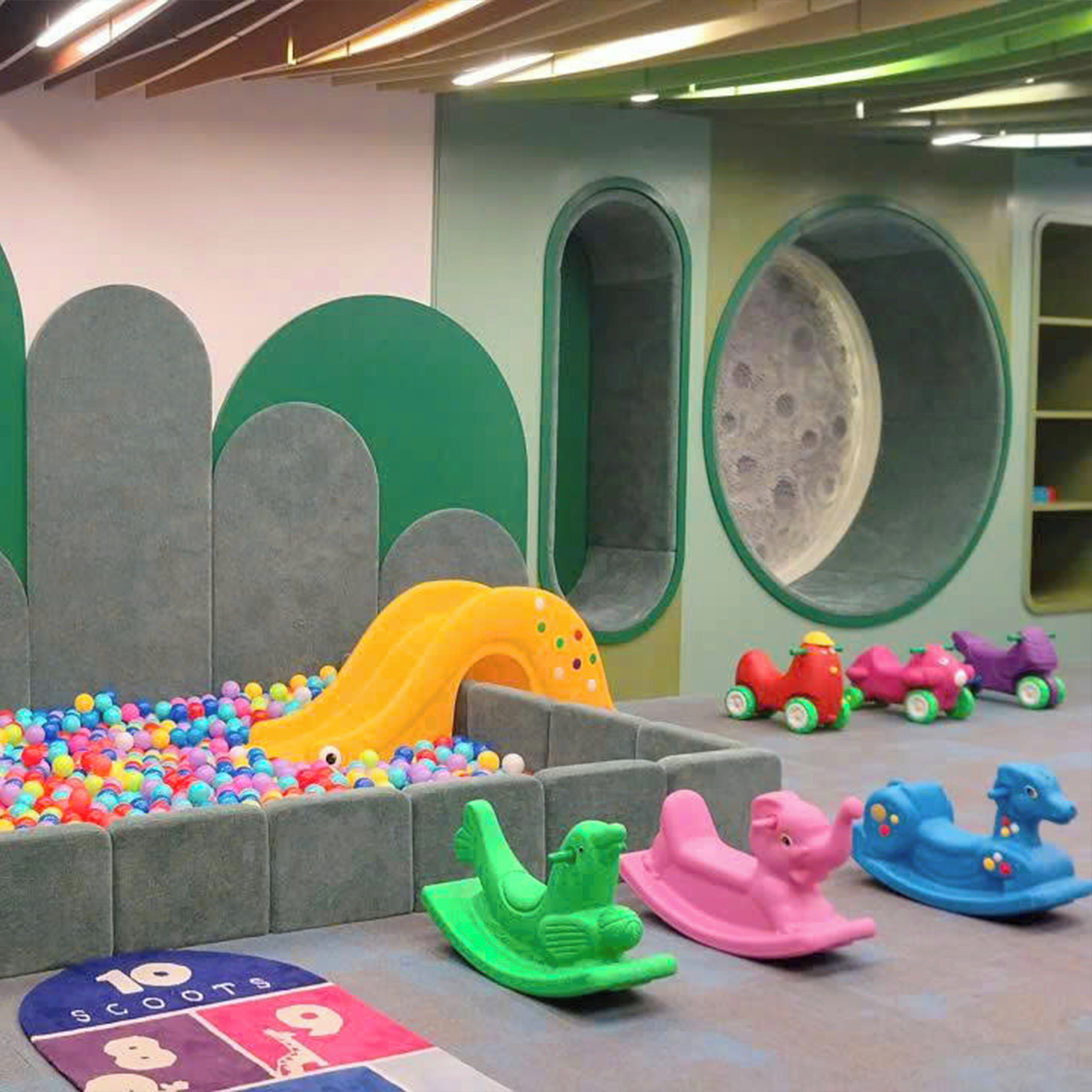Un espace de jeux pour enfants avec une piscine à balles, un toboggan et des véhicules jouets.