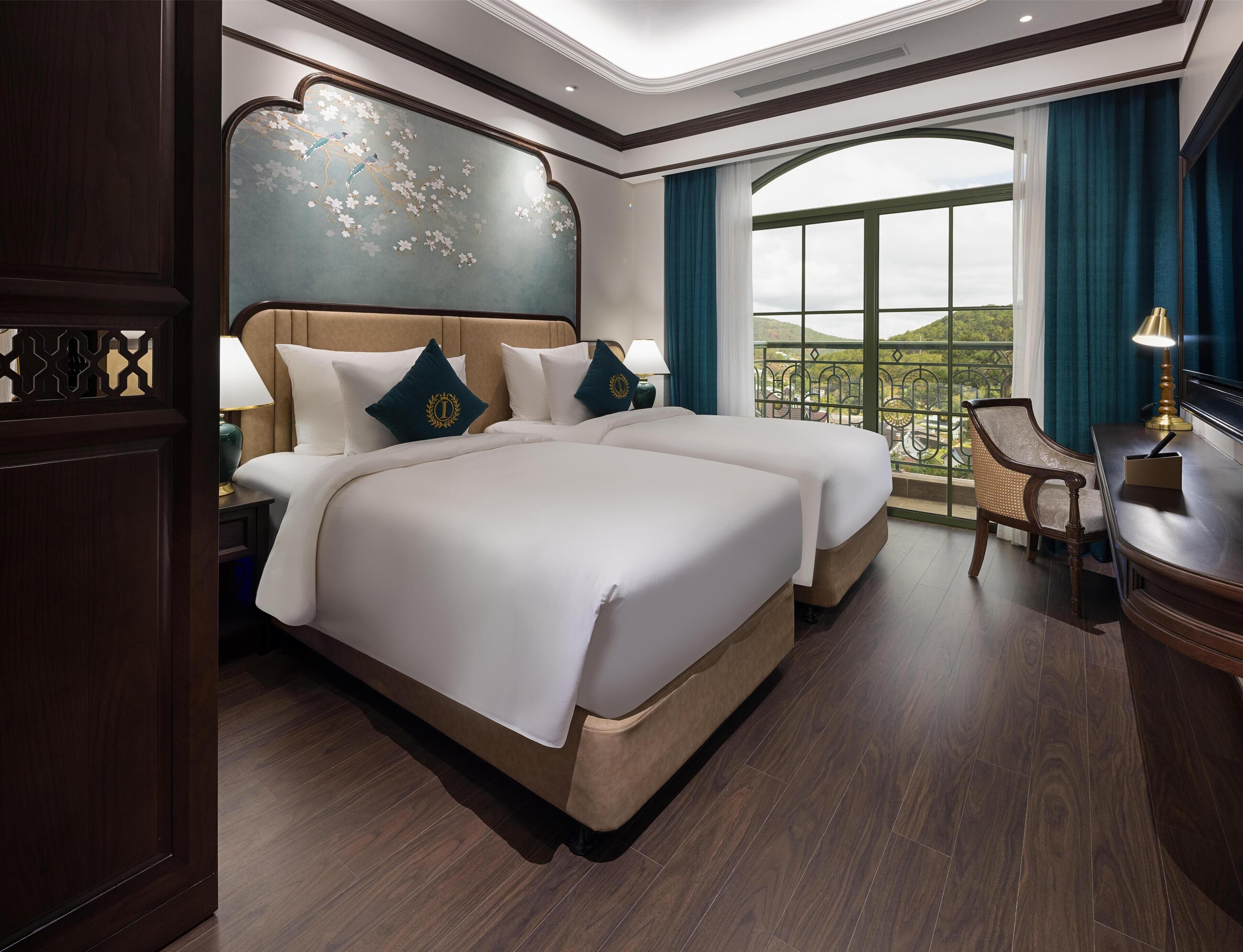 Habitación de hotel con una cama grande, un escritorio, una silla y un balcón con vistas.