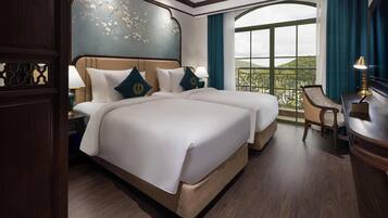 Habitación de hotel con una cama grande, un escritorio, una silla y un balcón con vistas.
