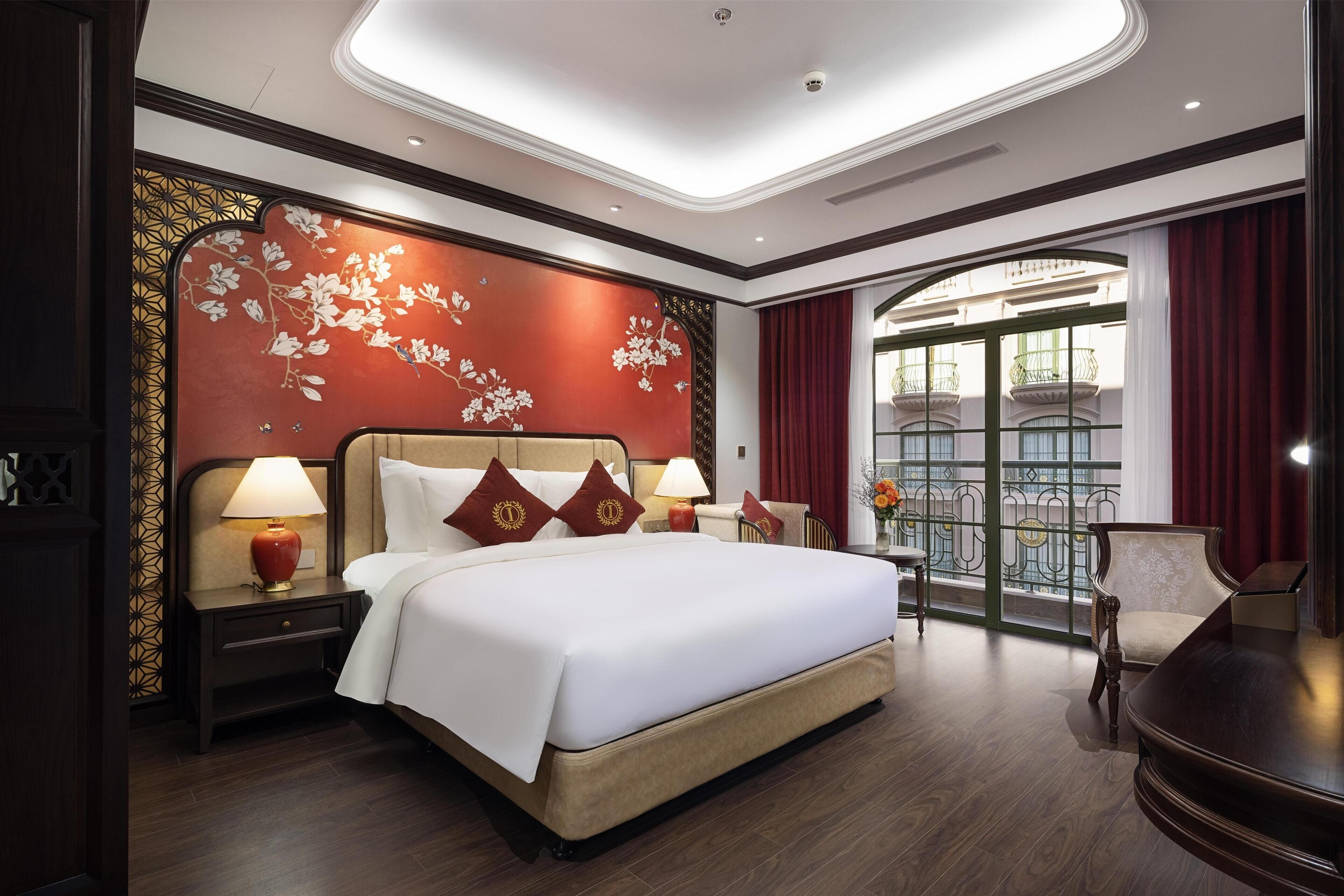 A hotel room with a large bed, two bedside tables with lamps, a chair, and a balcony view.