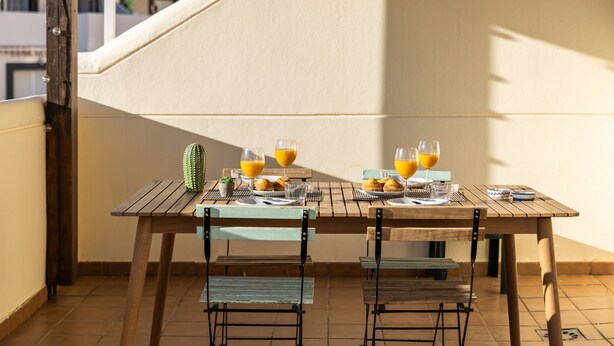 A wooden table with chairs, a cactus, and a plate of muffins and glasses of orange juice on a balcony. - Timon Stunning Sea Views by Alfresco Stays (Benalmádena)