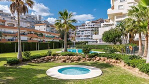 A residential area with a circular pool, palm trees, and multi-story buildings in the background. - Timon Stunning Sea Views by Alfresco Stays (Benalmádena)