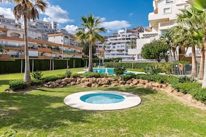 A residential area with a circular pool, palm trees, and multi-story buildings in the background. - Timon Stunning Sea Views by Alfresco Stays (Benalmádena)