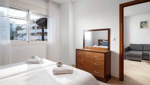 A hotel room with a bed, a wooden dresser, a mirror, a gray sofa, and a window with curtains. - Timon Stunning Sea Views by Alfresco Stays (Benalmádena)