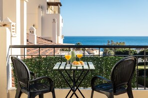 Een balkon met twee stoelen, een tafel en uitzicht op de oceaan.