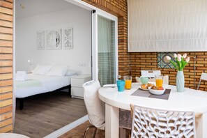 A modern hotel room with a bed, a dining area with a table and chairs, and a view through a glass door. - Seafront Escape by Alfresco Stays (Fuengirola)