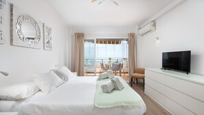 Ein Hotelzimmer mit Bett, Fernseher, Balkon mit Tisch und Stühlen sowie dekorativer Wandkunst.