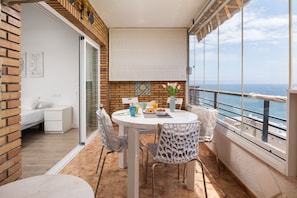 Ein Balkon mit Esstisch, Stühlen und Meerblick.