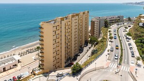 Ein Hotel an der Küste mit mehreren Etagen, Blick auf den Strand und einem Parkplatz.