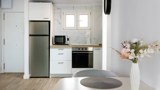 Eine moderne Küche mit Kühlschrank, Mikrowelle, Backofen und einem Essbereich mit Tisch und Stühlen.