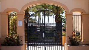 Una entrada protegida con un portón de metal, arcos y macetas con plantas.