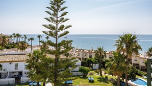 Um resort com piscina, palmeiras e vista para o mar.