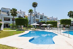 A swimming pool with a curved edge, surrounded by a white tiled deck. - AS EXT Ralbamar Xiv-1 (Mijas)