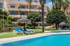 A hotel with a swimming pool, lounge chairs, and palm trees. - AS SM 175 in Mijas Costa (Mijas)