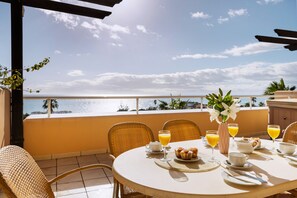 A round table with breakfast items, a vase with flowers, and a view of the sea. - AS MM B16 in Mijas Costa (Mijas)