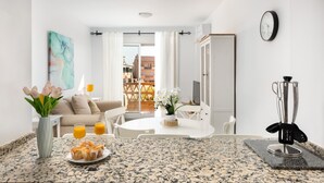 A modern kitchen with granite countertops, a dining area with a white table and chairs, and a view of buildings through a glass door. - AS EXT AL 2B1 1 6 in Mijas Costa (Mijas)