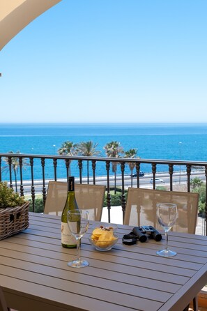 A table with a bottle of wine, two glasses, a bowl of snacks, binoculars, and a wicker basket on a balcony overlooking the ocean. - AS MDM 10 in Mijas Costa (Mijas)