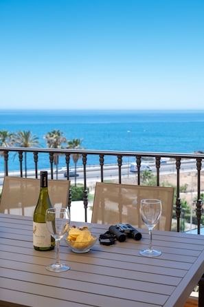 A table with a wine bottle, a glass, binoculars, and a bowl of snacks on a balcony with a view of the ocean. - AS MDM 10 in Mijas Costa (Mijas)
